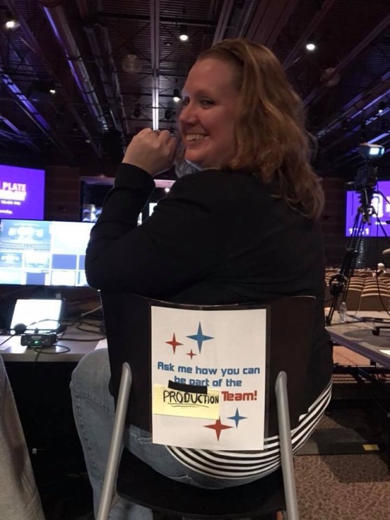Woman in a chair sitting at a production station in the back of an auditorium