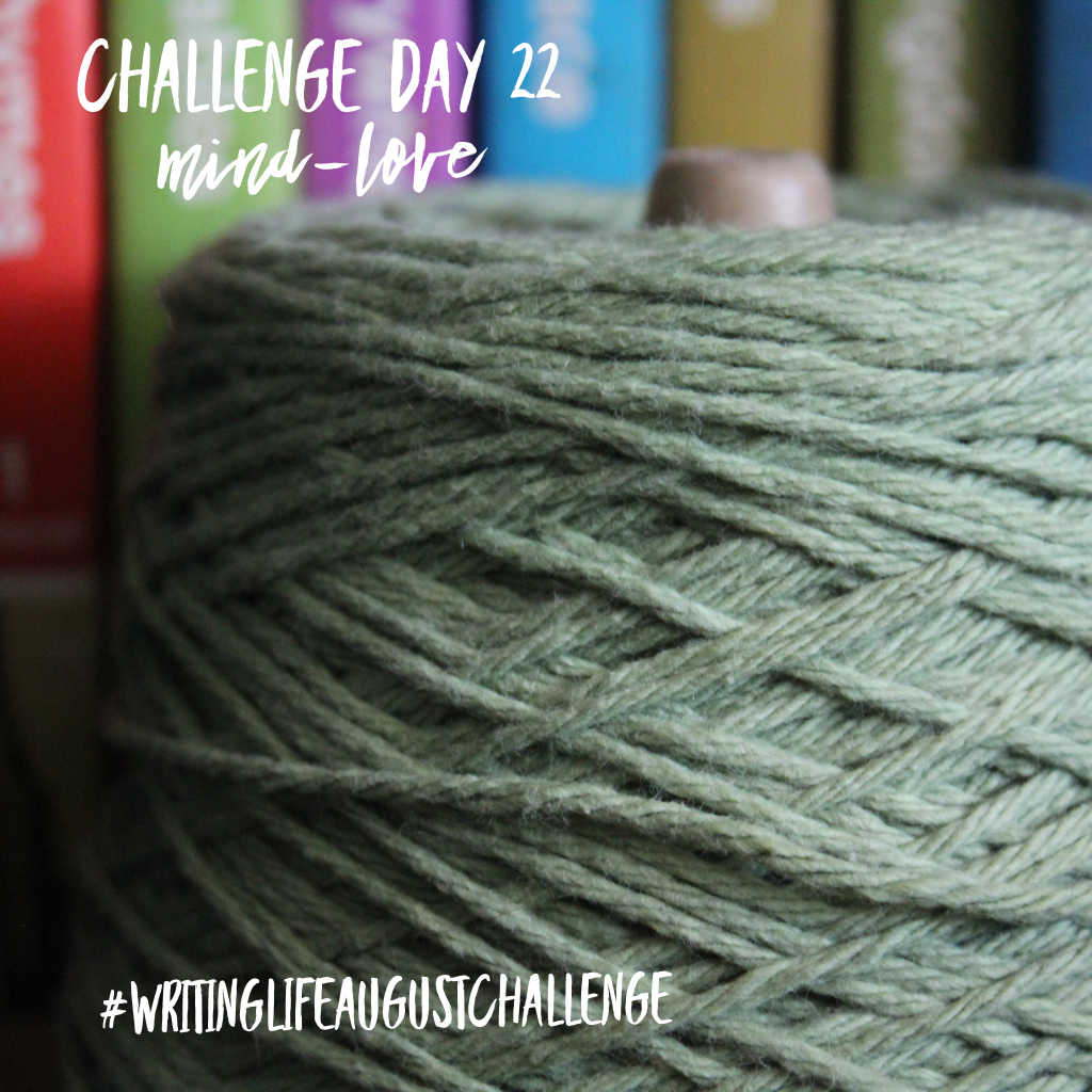 Large spool of green yarn sitting in front of a colorful row of books. Photo text: Challenge Day 22, mind-love. #writinglifeaugustchallenge 